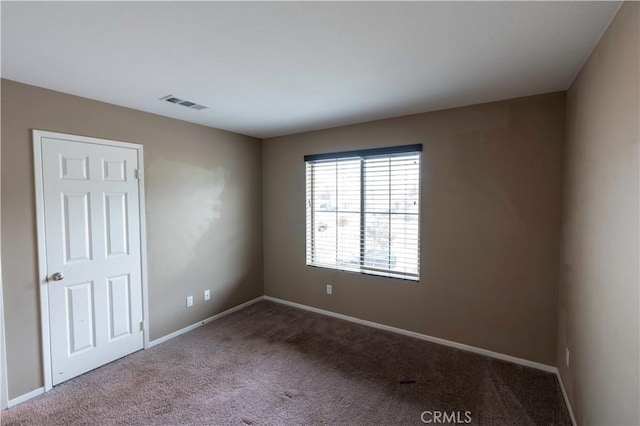 empty room with baseboards, visible vents, and carpet