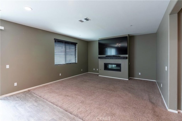 unfurnished living room with carpet, baseboards, a fireplace, and visible vents
