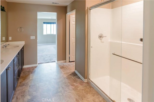 bathroom with baseboards, visible vents, a sink, and a stall shower