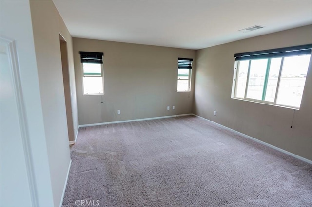 spare room featuring visible vents, baseboards, and light colored carpet