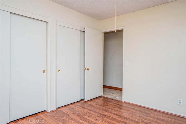 2136 Forbes Ave, Claremont, CA 91711 - unfurnished bedroom featuring a textured ceiling, light wood finished floors, and two closets