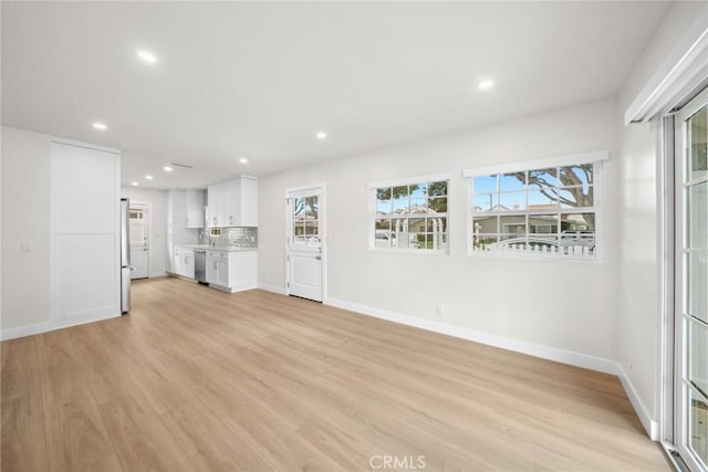 unfurnished living room with recessed lighting, baseboards, and light wood-type flooring
