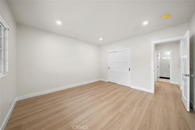 unfurnished bedroom with recessed lighting, baseboards, a closet, and light wood finished floors