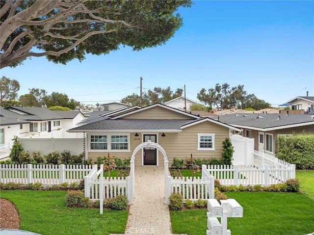 view of front facade with a shingled roof, fence private yard, and a front yard