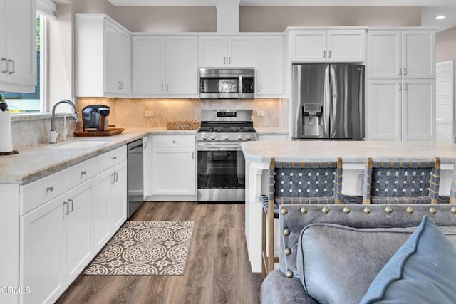kitchen with a sink, appliances with stainless steel finishes, wood finished floors, and white cabinetry