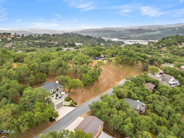 birds eye view of property featuring a wooded view and a water and mountain view