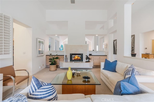 living area featuring light colored carpet, baseboards, and a tiled fireplace