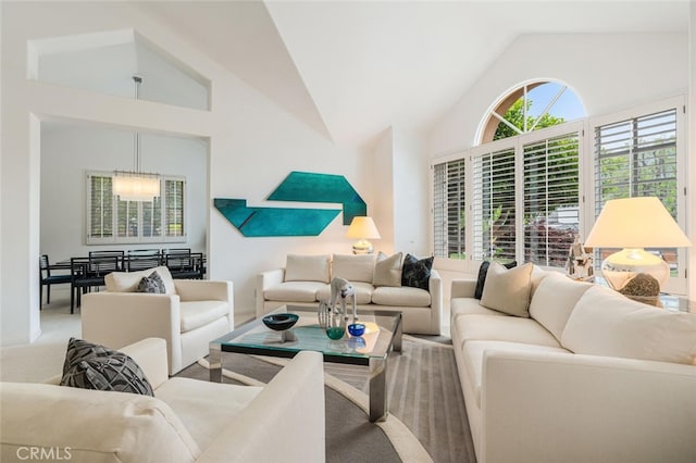 living room with an inviting chandelier, carpet, and high vaulted ceiling
