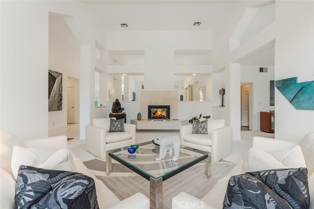 living room featuring high vaulted ceiling, a fireplace, and visible vents