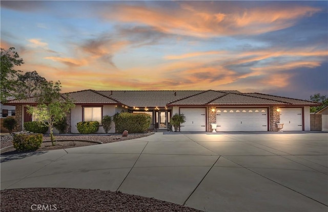 13484 Capella Rd, Apple Valley, CA 92308 - view of front of house with driveway, stucco siding, a garage, a tile roof, and stone siding