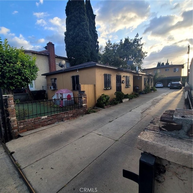 exterior space featuring fence, stucco siding, and a chimney