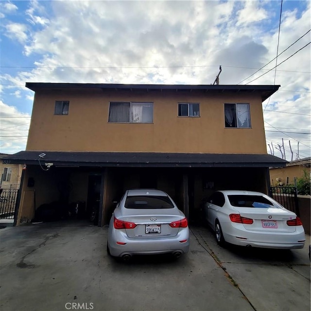 view of front facade featuring fence, stucco siding, concrete driveway, and a garage