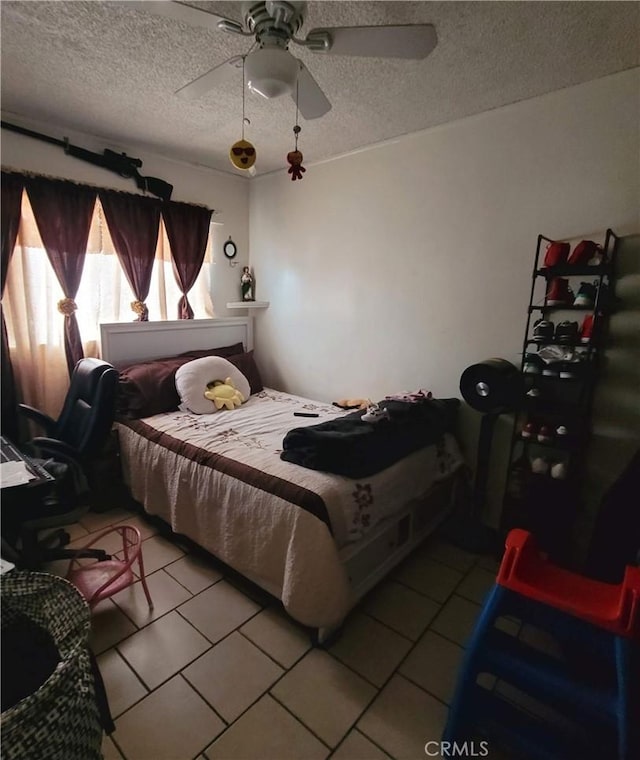 bedroom featuring light tile patterned floors, ceiling fan, and a textured ceiling