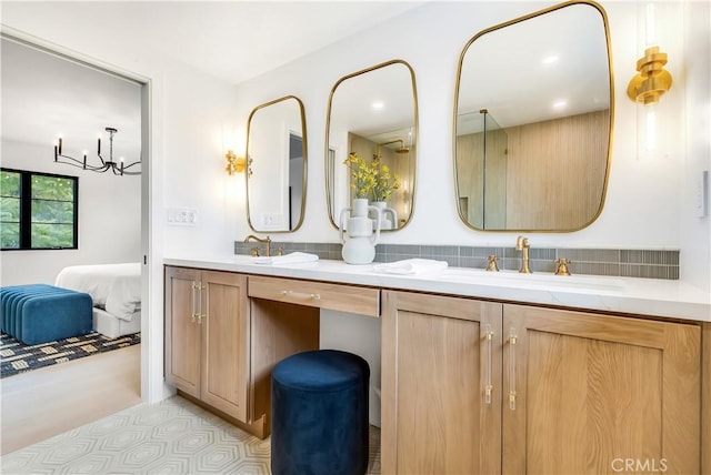 ensuite bathroom featuring connected bathroom, double vanity, an inviting chandelier, and a sink