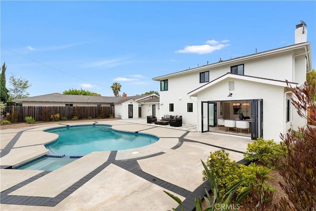 view of swimming pool featuring a storage unit, a pool with connected hot tub, an outdoor hangout area, a fenced backyard, and a patio area