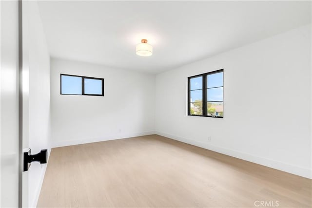 empty room with light wood-style floors, baseboards, and a healthy amount of sunlight