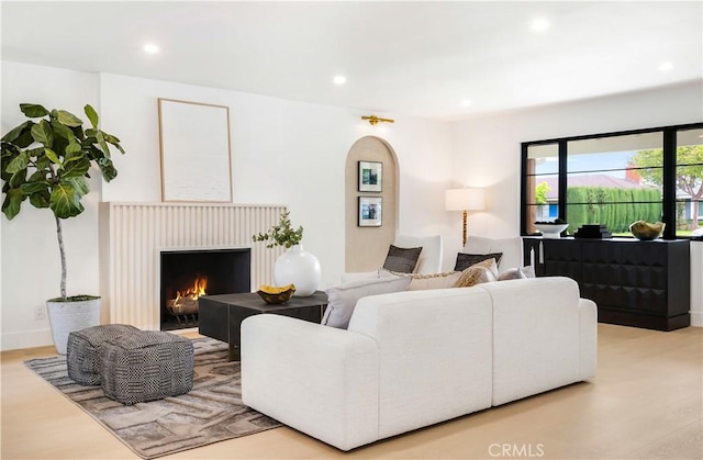 living room with recessed lighting, a lit fireplace, and wood finished floors