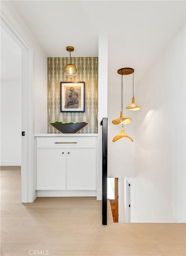 bar featuring light wood-type flooring and decorative light fixtures