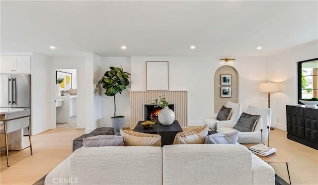 living area featuring light wood-type flooring, a lit fireplace, and recessed lighting