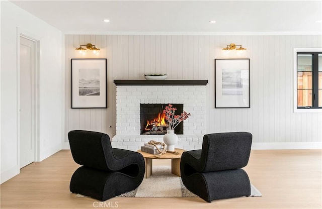 living area featuring a brick fireplace, recessed lighting, baseboards, wood finished floors, and ornamental molding