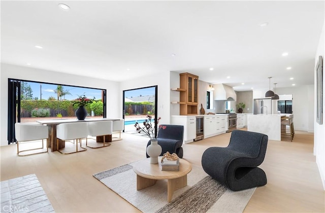 living area with light wood-type flooring, recessed lighting, plenty of natural light, and wine cooler