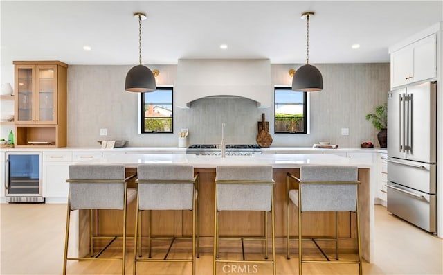 kitchen with beverage cooler, plenty of natural light, premium range hood, and high quality fridge