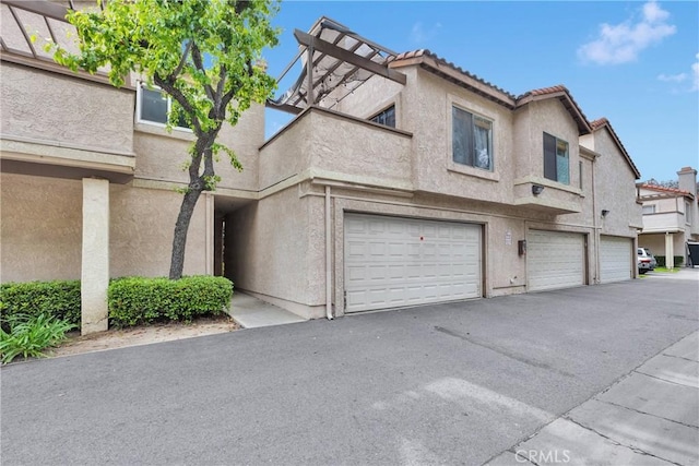 exterior space with an attached garage, stucco siding, driveway, and a tile roof