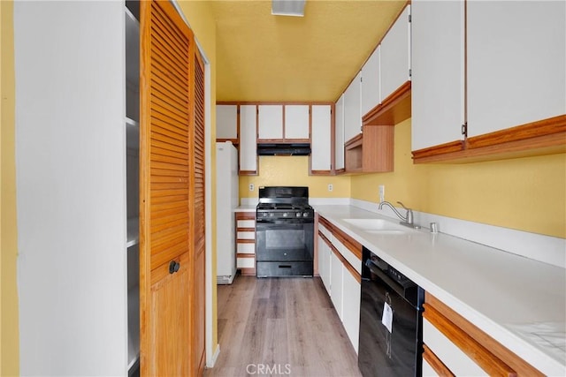 kitchen featuring light countertops, black appliances, light wood-style floors, under cabinet range hood, and white cabinetry