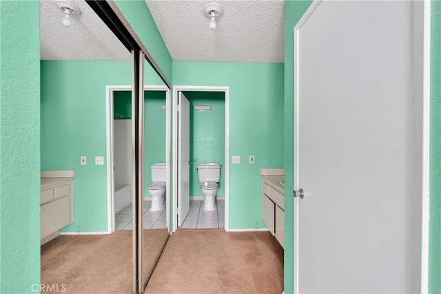 bathroom with vanity, tile patterned flooring, toilet, and a textured ceiling