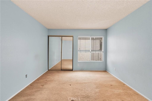 unfurnished bedroom featuring a closet, a textured ceiling, carpet, and baseboards