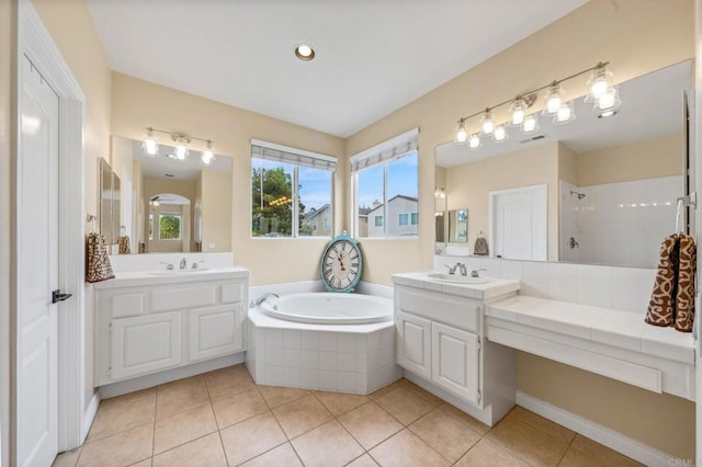 bathroom featuring tile patterned flooring, a tile shower, a sink, and a garden tub