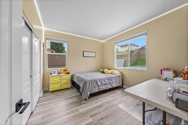 bedroom with baseboards, light wood-style flooring, and a closet