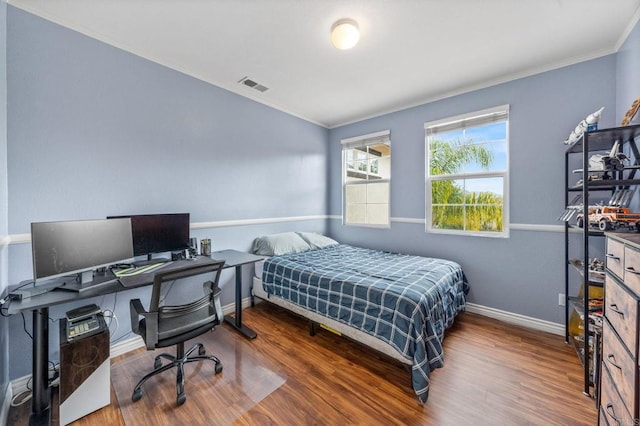 bedroom with visible vents, ornamental molding, baseboards, and wood finished floors