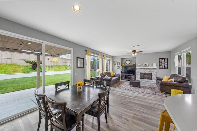 dining space featuring a ceiling fan, wood finished floors, a wealth of natural light, and a fireplace