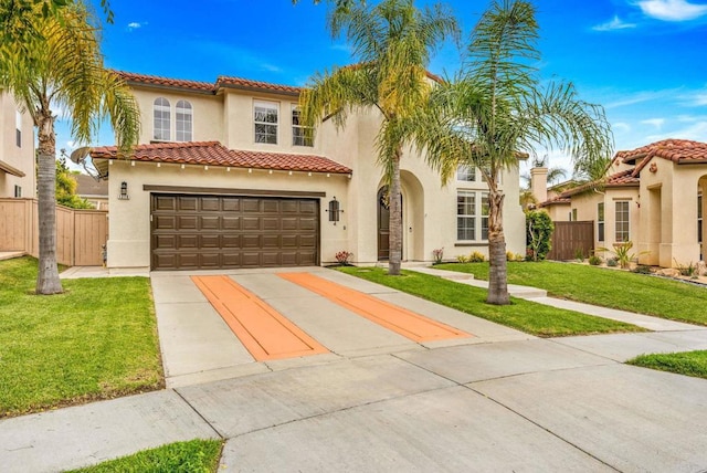 mediterranean / spanish-style home with stucco siding, fence, a front yard, and concrete driveway