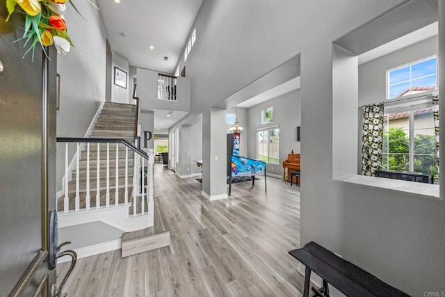stairs featuring baseboards, plenty of natural light, wood finished floors, and a towering ceiling