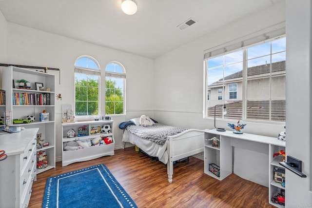 bedroom with visible vents, multiple windows, and wood finished floors
