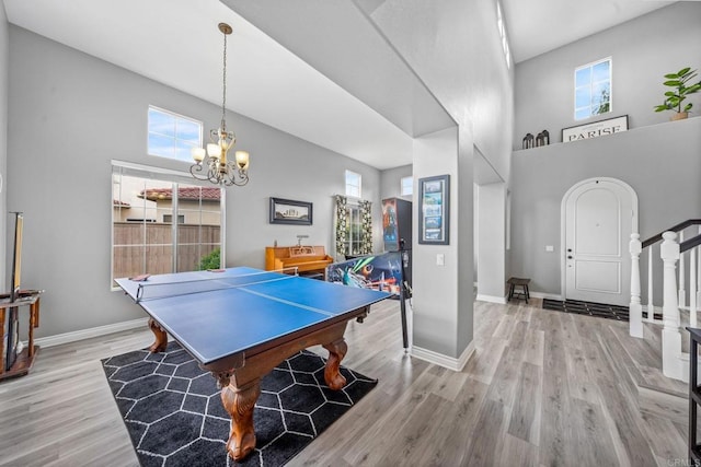 game room featuring a high ceiling, a healthy amount of sunlight, and wood finished floors