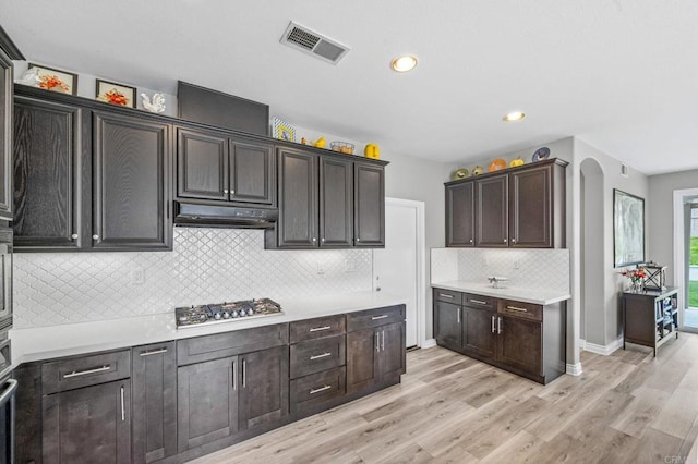 kitchen featuring visible vents, light countertops, stainless steel gas stovetop, under cabinet range hood, and light wood-style flooring