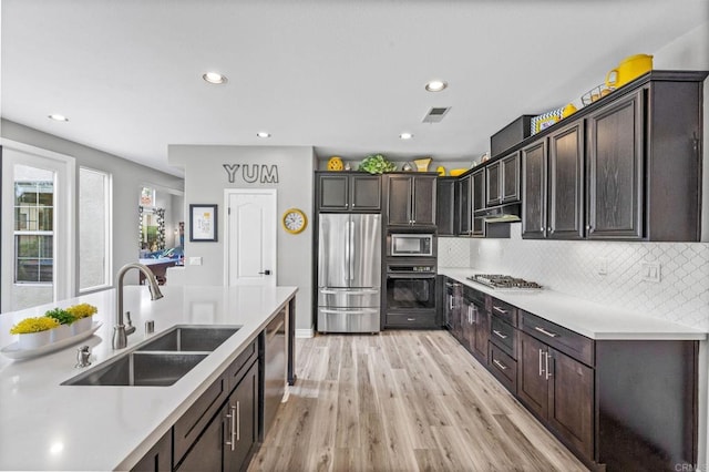 kitchen with visible vents, light countertops, a sink, light wood-style flooring, and stainless steel appliances