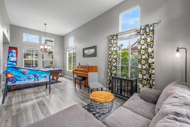recreation room featuring baseboards, a high ceiling, a chandelier, and wood finished floors