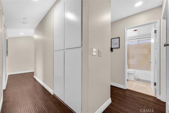corridor with baseboards, recessed lighting, and wood finished floors