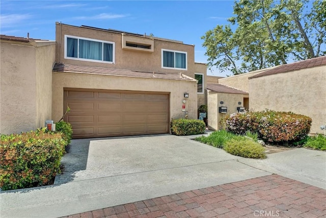 view of front facade with an attached garage, stucco siding, and driveway