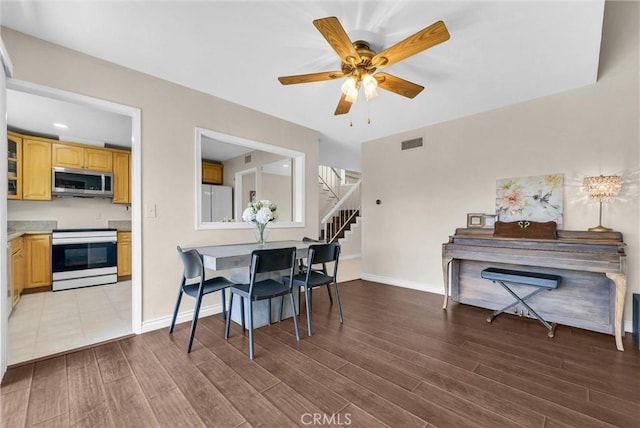dining area featuring stairs, a ceiling fan, baseboards, wood finished floors, and visible vents