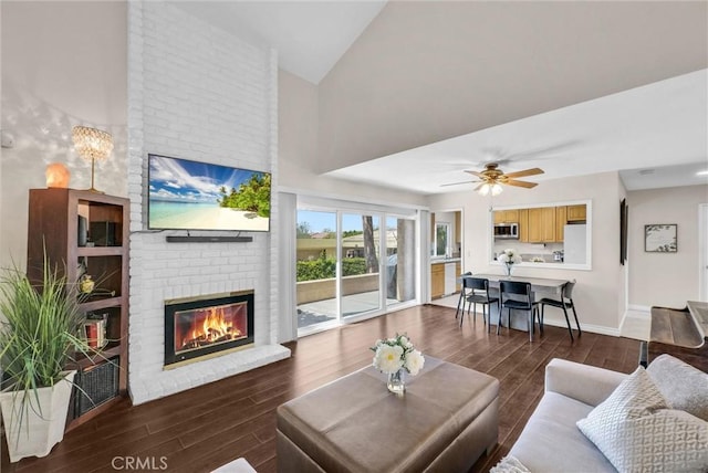 living room with a fireplace, high vaulted ceiling, a ceiling fan, baseboards, and wood finished floors