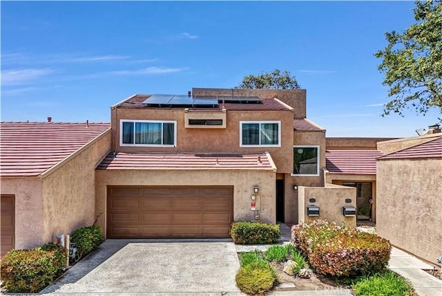 view of front facade with a garage, solar panels, stucco siding, and driveway