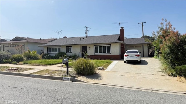 single story home with a garage, stucco siding, a chimney, and driveway