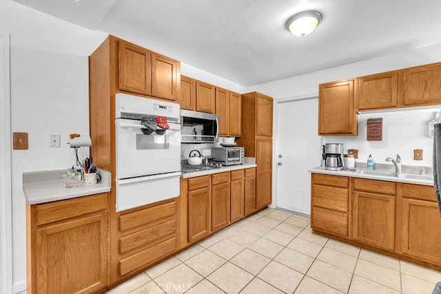kitchen with light tile patterned flooring, light countertops, a sink, appliances with stainless steel finishes, and a warming drawer