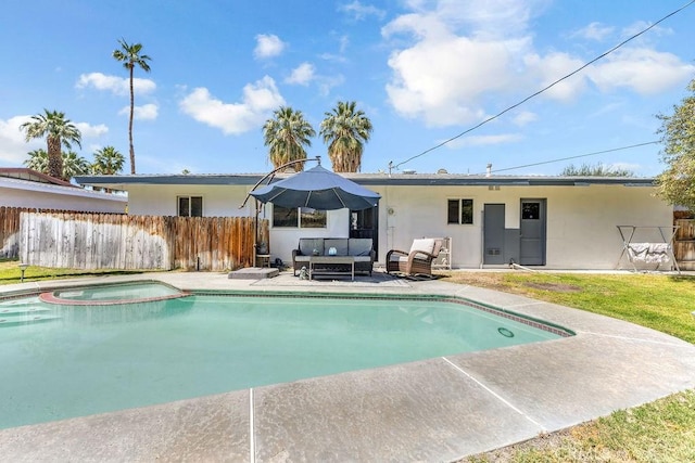 rear view of house with fence, a pool with connected hot tub, an outdoor hangout area, stucco siding, and a patio