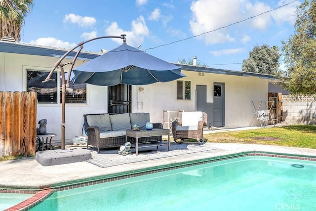 rear view of house featuring a fenced in pool, outdoor lounge area, a patio area, and stucco siding